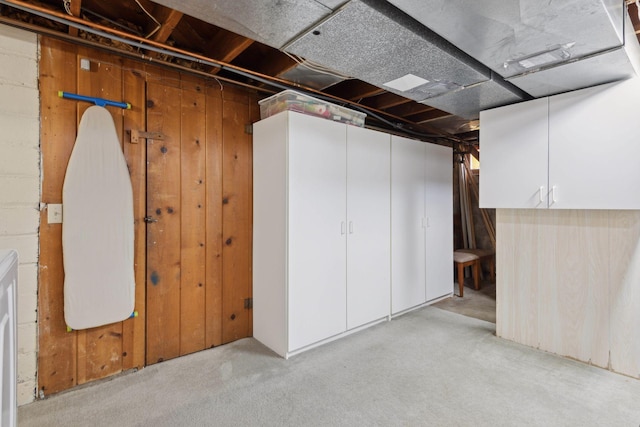 basement with light carpet and wooden walls