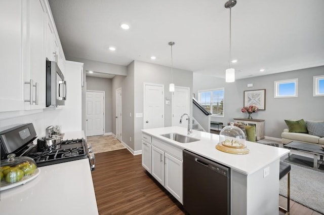 kitchen with gas stove, sink, a center island with sink, black dishwasher, and hanging light fixtures