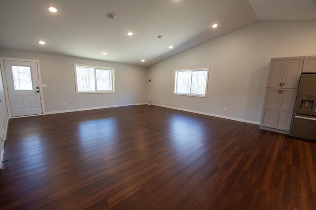 unfurnished living room with a healthy amount of sunlight, dark wood-style floors, baseboards, and lofted ceiling