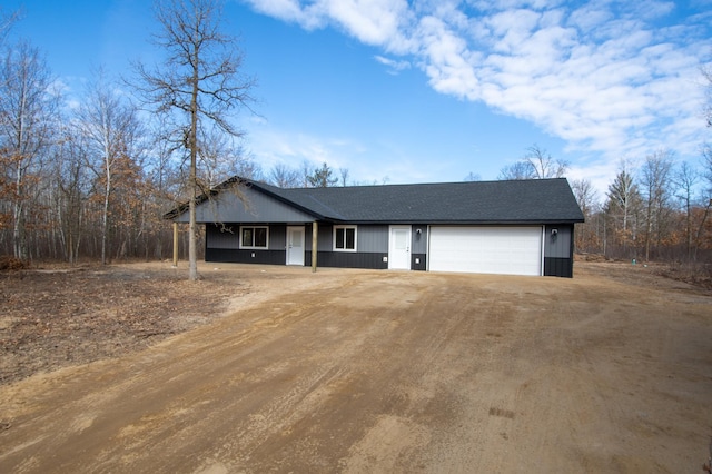 view of front of property with dirt driveway and a garage