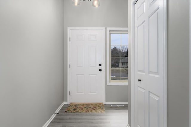 doorway to outside featuring hardwood / wood-style flooring and a notable chandelier