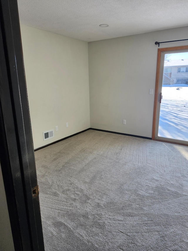 carpeted spare room featuring a textured ceiling