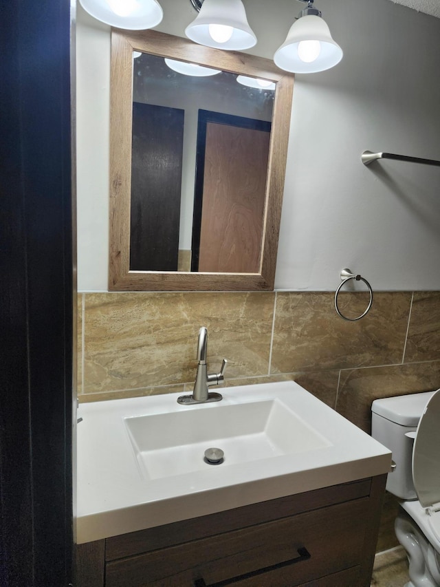 bathroom with toilet, vanity, and tile walls