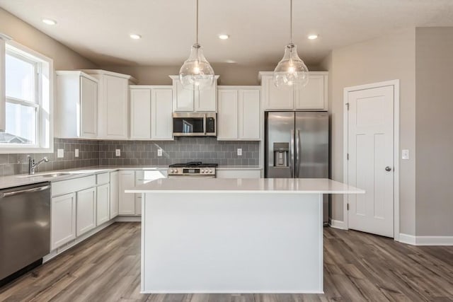 kitchen with a center island, white cabinets, pendant lighting, and appliances with stainless steel finishes