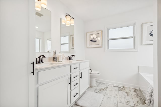 bathroom with a washtub, toilet, and vanity