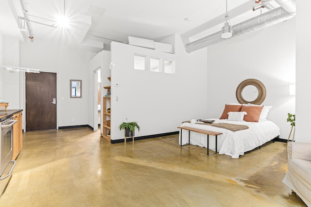 bedroom with a high ceiling and concrete floors