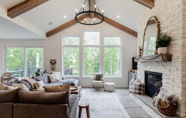 living area featuring a stone fireplace, beam ceiling, a notable chandelier, and wood finished floors