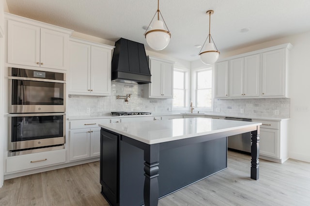 kitchen with custom exhaust hood, stainless steel appliances, light countertops, and a sink