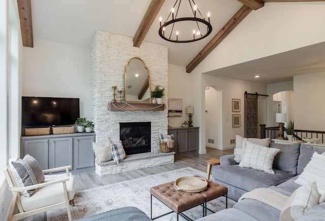 living area with arched walkways, high vaulted ceiling, a barn door, and wood finished floors