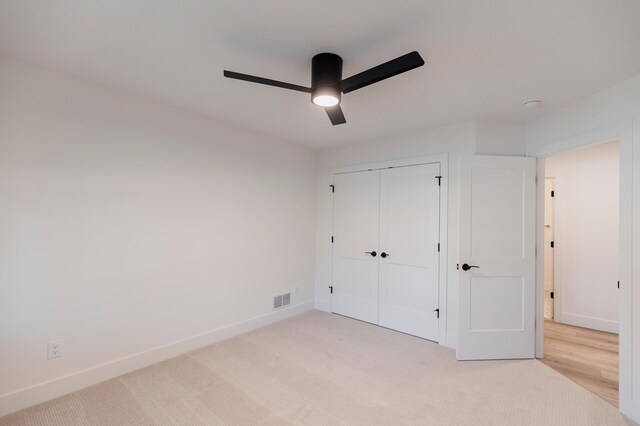unfurnished bedroom featuring baseboards, visible vents, a closet, and light carpet