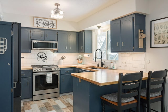 kitchen with blue cabinets, sink, a kitchen breakfast bar, kitchen peninsula, and stainless steel appliances