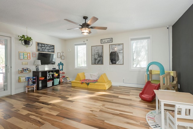 rec room with ceiling fan, wood-type flooring, and a textured ceiling