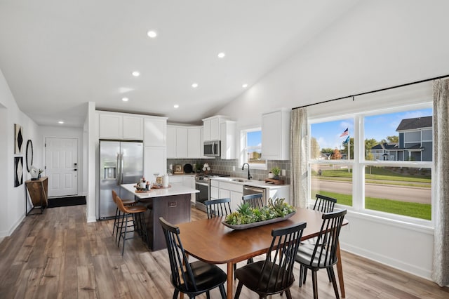 dining room featuring light hardwood / wood-style flooring, lofted ceiling, and sink