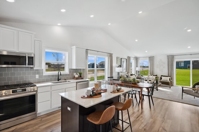 kitchen with backsplash, sink, a kitchen island, white cabinetry, and stainless steel appliances