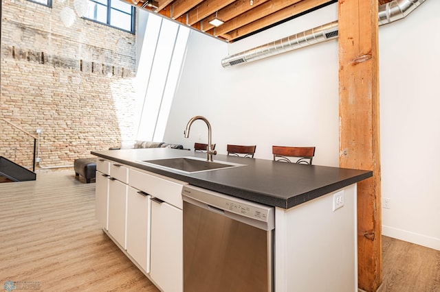 kitchen with white cabinetry, light hardwood / wood-style floors, dishwasher, and sink