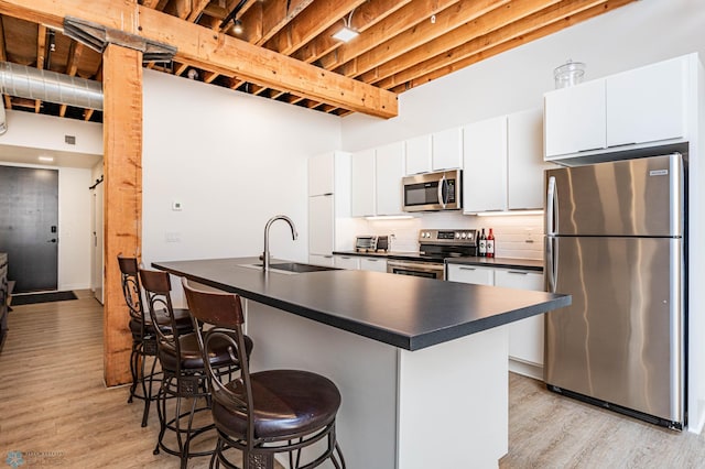 kitchen featuring white cabinetry, sink, stainless steel appliances, and a kitchen bar