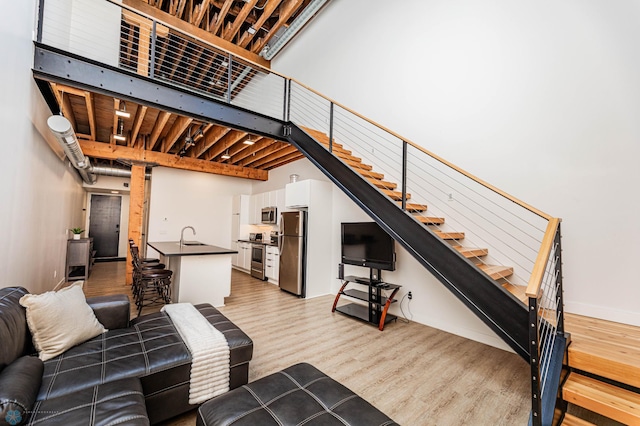 living room with sink, light wood-type flooring, and a high ceiling