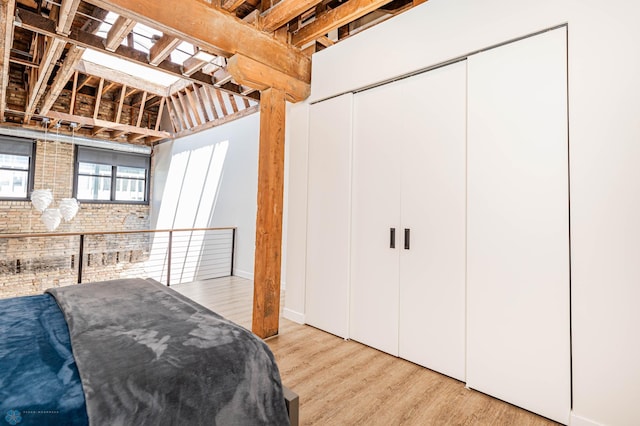 bedroom with brick wall and light wood-type flooring