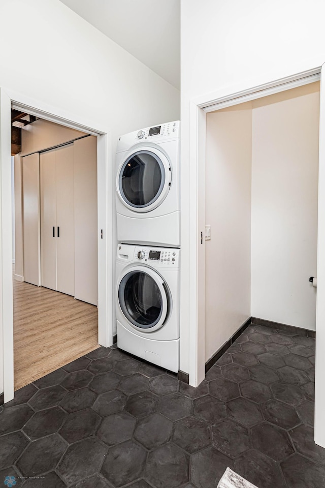 clothes washing area with dark wood-type flooring and stacked washer / dryer