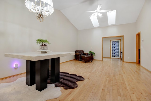 sitting room featuring ceiling fan with notable chandelier, hardwood / wood-style flooring, and vaulted ceiling with skylight