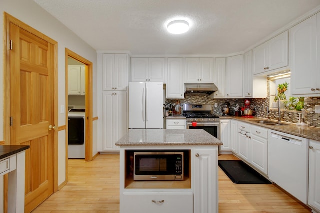 kitchen featuring washer / dryer, white cabinets, a kitchen island, and appliances with stainless steel finishes