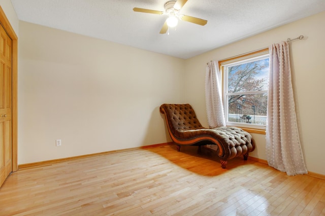 sitting room featuring ceiling fan, light hardwood / wood-style flooring, and a textured ceiling