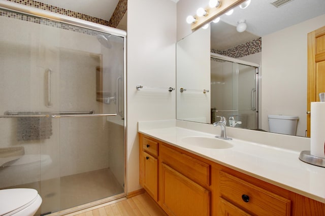 bathroom featuring vanity, a shower with shower door, and toilet