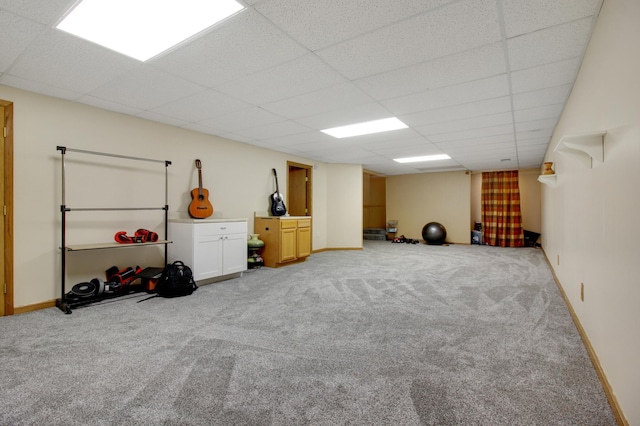 basement with a paneled ceiling and light carpet