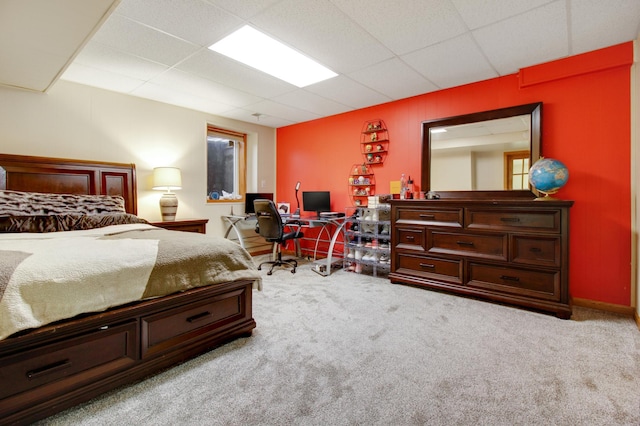 bedroom featuring a drop ceiling and light carpet