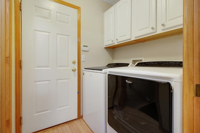 clothes washing area featuring washing machine and clothes dryer and cabinets