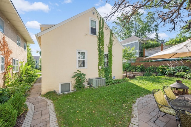 view of side of property featuring cooling unit, a yard, and a patio area