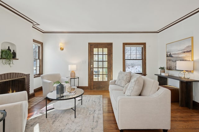 living room featuring a brick fireplace, ornamental molding, and dark hardwood / wood-style floors