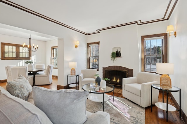 living room featuring hardwood / wood-style floors, a fireplace, ornamental molding, and a chandelier