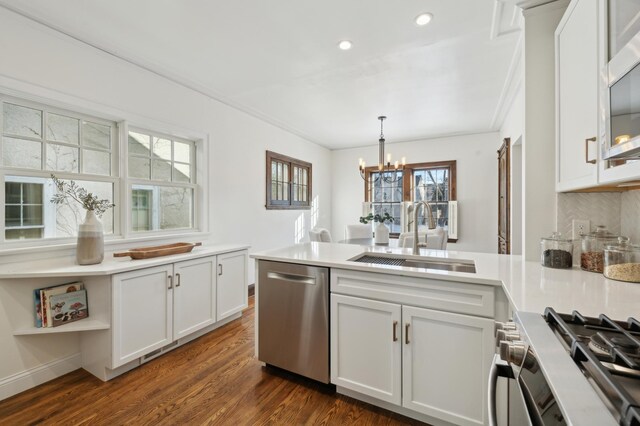 kitchen with white cabinetry, stainless steel appliances, decorative light fixtures, and sink