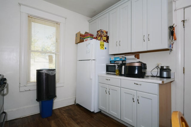 kitchen with dark wood-type flooring, white cabinets, and white fridge