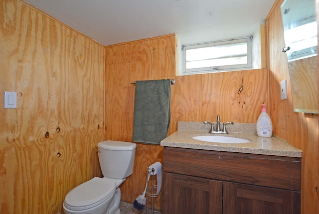 bathroom with wooden walls, vanity, and toilet