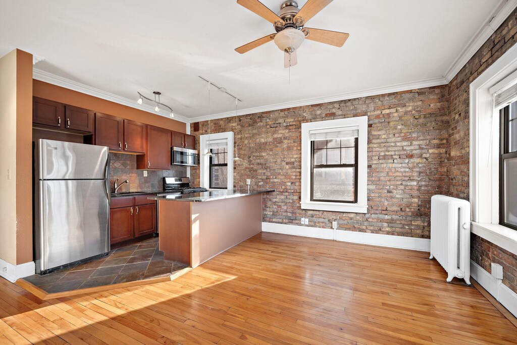 1901 Stevens Ave Unit 301, Minneapolis, MN 55403 - kitchen featuring appliances with stainless steel finishes, rail lighting, radiator, brick wall, and sink