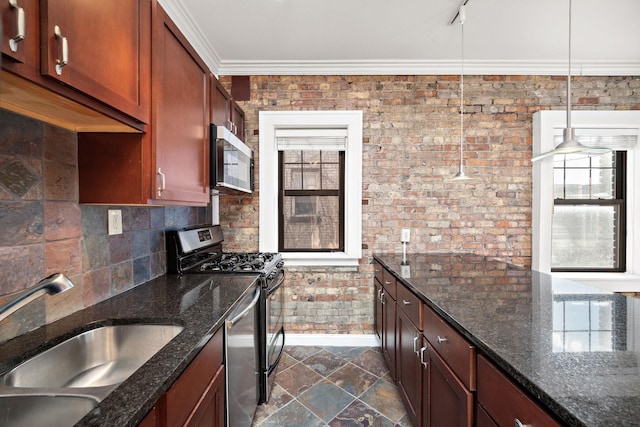 kitchen featuring sink, stainless steel appliances, brick wall, dark stone countertops, and decorative light fixtures