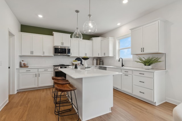 kitchen featuring white cabinets, a center island, light hardwood / wood-style floors, and stainless steel appliances