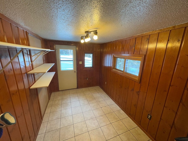 entryway with a textured ceiling, rail lighting, and wood walls