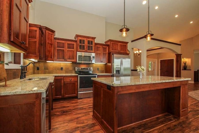 kitchen featuring dark hardwood / wood-style flooring, backsplash, stainless steel appliances, sink, and a center island