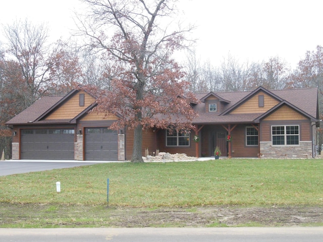 craftsman-style home featuring a front yard, stone siding, driveway, and an attached garage