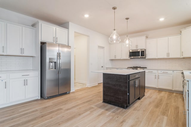 kitchen featuring tasteful backsplash, white cabinetry, hanging light fixtures, and appliances with stainless steel finishes