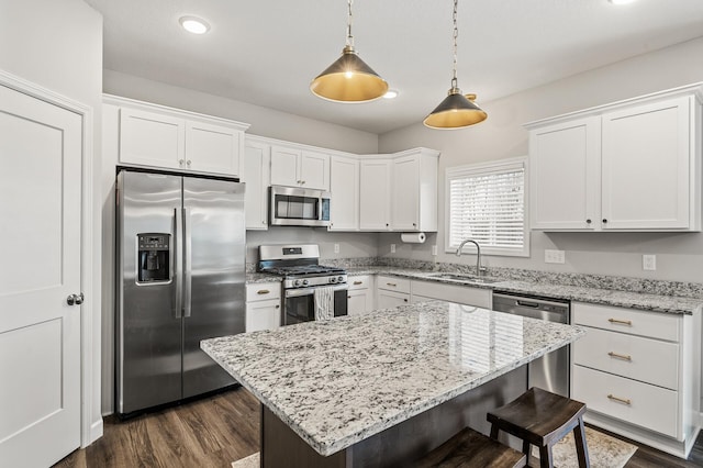 kitchen featuring sink, decorative light fixtures, a kitchen island, stainless steel appliances, and white cabinets