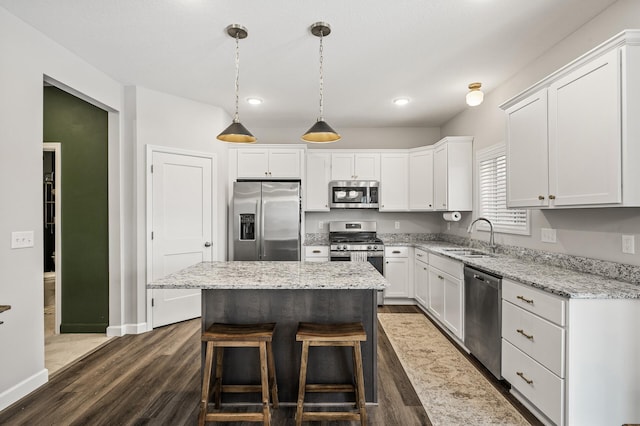 kitchen featuring white cabinetry, decorative light fixtures, stainless steel appliances, and a center island