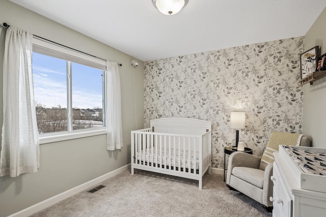 carpeted bedroom featuring a nursery area