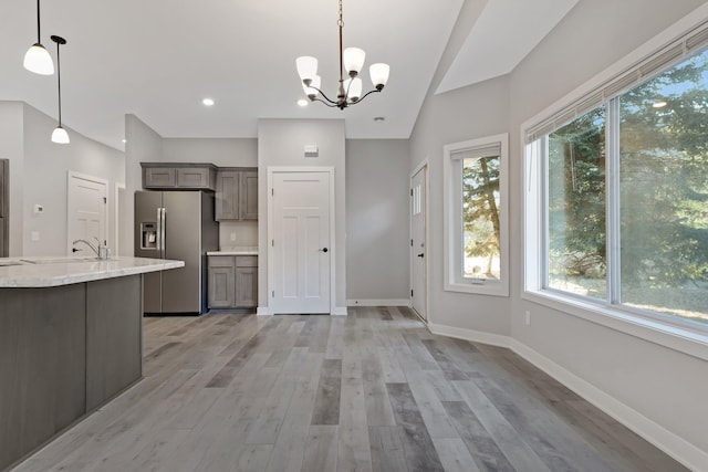 kitchen with a chandelier, stainless steel refrigerator with ice dispenser, a wealth of natural light, and hanging light fixtures