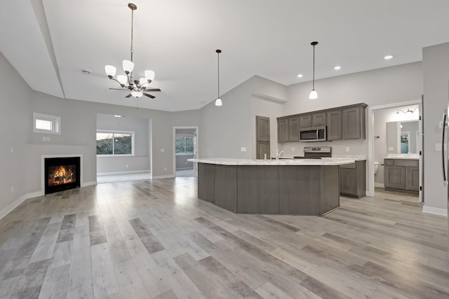 kitchen featuring appliances with stainless steel finishes, a towering ceiling, a center island with sink, and sink