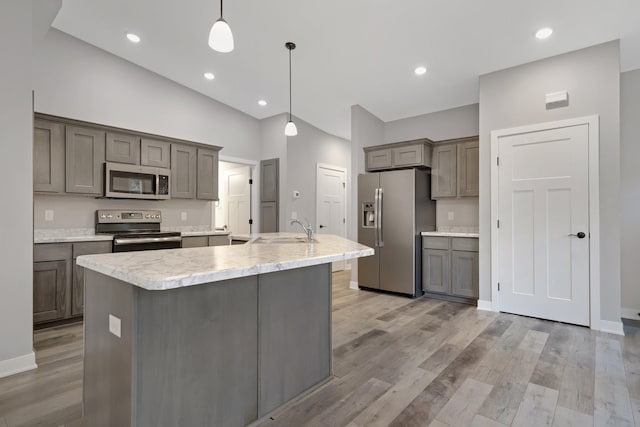 kitchen with a kitchen island with sink, sink, hanging light fixtures, and appliances with stainless steel finishes