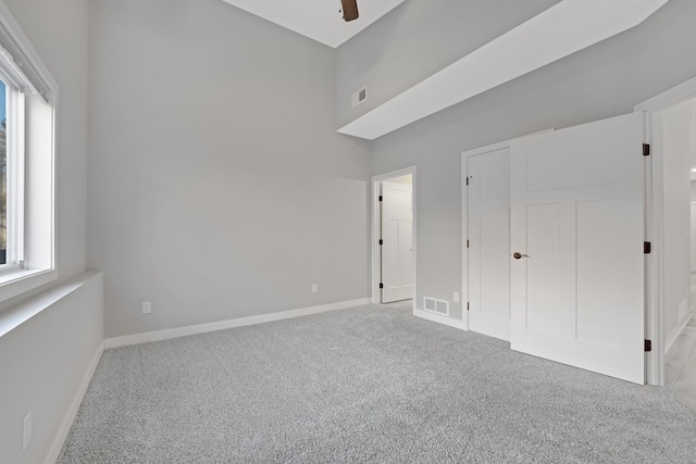 unfurnished bedroom with ceiling fan, light colored carpet, and multiple windows